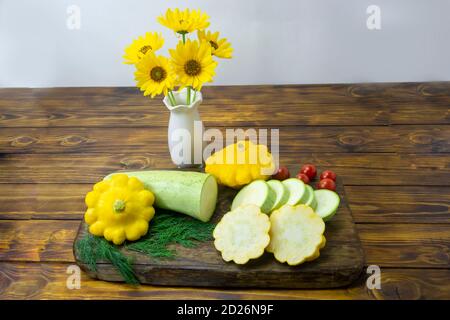 La courgette et la petite courge jaune sur une planche à découper sont tranchées. Concept de régime mono, alimentation saine. Mise au point sélective, arrière-plan en bois sombre. Banque D'Images