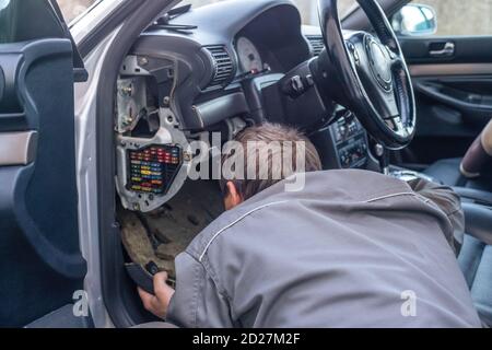 Homme mécanicien de voiture regardant sous l'espace de direction à l'intérieur de la voiture. Concept de réparation de voiture Banque D'Images