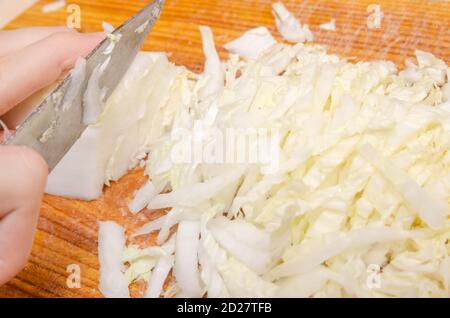 Mains de femmes avec un couteau coupé chou de Pékin vert clair. Cuisson de salade de légumes, vue latérale Banque D'Images