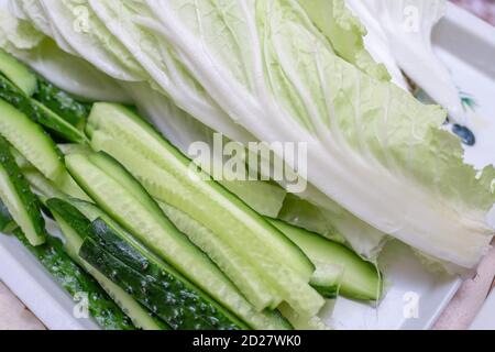 Tranches de concombre frais et feuilles de chou péké sur une assiette gros plan Banque D'Images