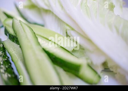 Tranches de concombre frais et feuilles de chou péké sur une assiette gros plan Banque D'Images