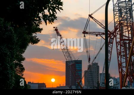 Le soleil se couche derrière le chantier de construction du stade national du Japon. Banque D'Images