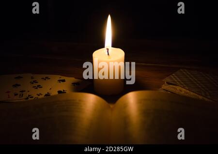 atmosphère mystique, cartes, un livre, une bougie allumée dans le noir sur une table en bois. Concept ésotérique, prédictions et récits de fortune Banque D'Images