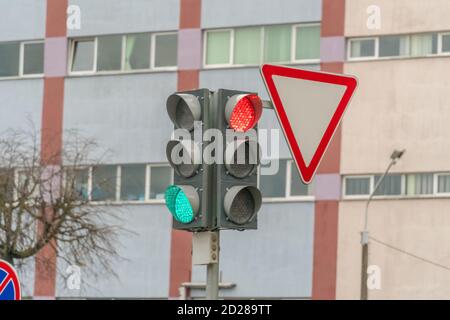 Feu de circulation avec un feu vert et rouge allumé sur le intersection avec le panneau route principale sur l'arrière-plan de le bâtiment Banque D'Images