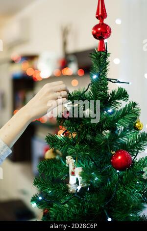 Gros plan des mains de femmes décorant le dessus d'un arbre de Noël. Banque D'Images