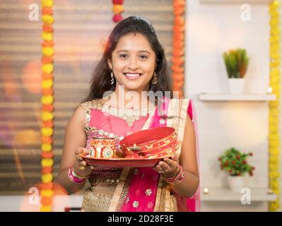 Portret photo d'une femme mariée indienne en robe traditionnelle tenant Karva Chauth Thali ou assiette pendant le festival indien hindou de karwa chauth. Banque D'Images