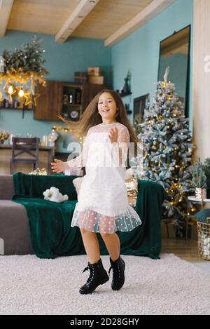 Fille élégante dans une robe blanche tourbillonne sur le fond D'un arbre de Noël dans le salon dans le maison Banque D'Images