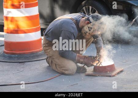 Soudure sur la plaque en acier travailleur street, NYC Banque D'Images