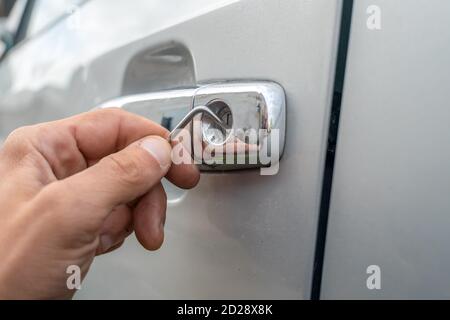 Voleur de voiture. Gros plan - des mains d'un homme ouvrant la voiture avec un verrou Banque D'Images