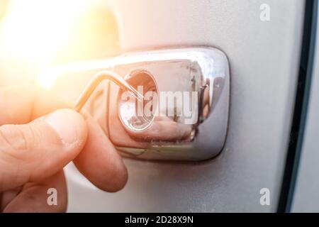 Voleur de voiture. Gros plan - des mains d'un homme ouvrant la voiture avec un verrou. Photo avec éclairage, lumière Banque D'Images