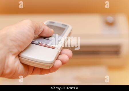 la main de l'homme avec une télécommande est dirigée vers le climatisation en gros plan Banque D'Images