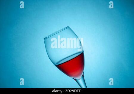 verre de vin rouge sur fond bleu en mouvement. Gel des liquides en mouvement. Verre de vin rouge en angle avec espace de copie Banque D'Images