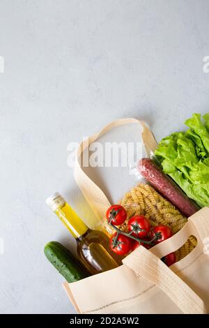 Ensemble de produits d'épicerie dans un sac à ficelle de pâtes, huile, salade, tomate, saucisse. Livraison d'aliments à domicile commandée en ligne sur fond gris. Ordre Internet de Banque D'Images