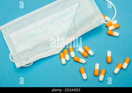 Masque médical, capsules orange-blanc sur fond bleu gros plan Banque D'Images
