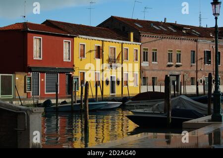 Venise, île de Burano, vue sur un canal dans l'après-midi lumière, ciel clair et sombre après une tempête, traditionnelles vénitiennes façades peintes reflet Banque D'Images