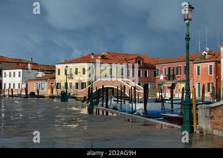 Venise, île de Burano, vue sur un canal dans l'après-midi lumière, ciel clair et sombre après une tempête, traditionnelles vénitiennes façades peintes reflet Banque D'Images