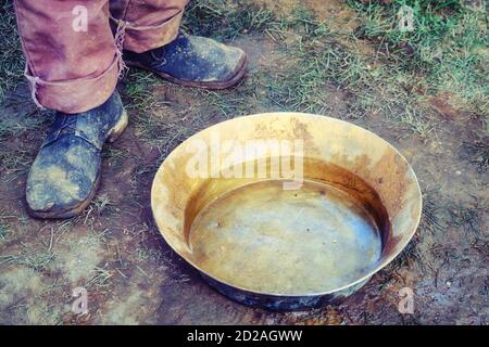 Lavage de l'or en plateau par les colons américains dans l'Ouest sauvage. La reconstruction historique de l'extraction de l'or à la main dans l'ancien temps. Un homme se tient à côté de Banque D'Images