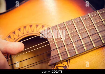 Gros plan de la main d'un joueur de guitare sur une guitare acoustique marron Banque D'Images