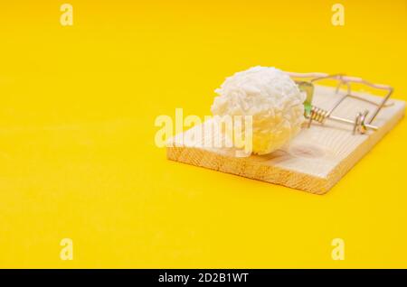 Bonbons Raffaello dans un mousetrap sur fond jaune. Concept de santé, régime alimentaire Banque D'Images