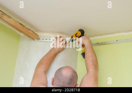 Fixation au guide mural pour un plafond extensible. Les réparateurs font l'installation d'un plafond extensible Banque D'Images