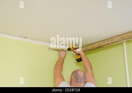 Fixation au guide mural pour un plafond extensible. Les réparateurs font l'installation d'un plafond extensible Banque D'Images