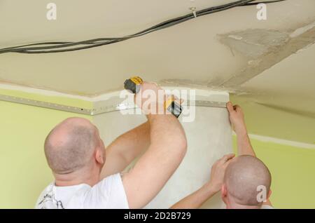 Fixation au guide mural pour un plafond extensible. Les réparateurs font l'installation d'un plafond extensible Banque D'Images