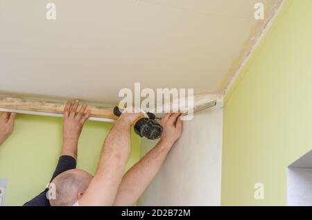 Fixation au guide mural pour un plafond extensible. Les réparateurs font l'installation d'un plafond extensible Banque D'Images