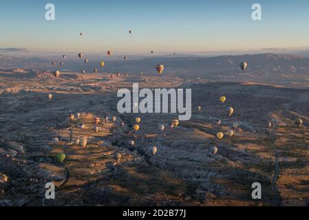 Vue panoramique avec des pelons survolant le paysage de Cappadoce à la lever du soleil Banque D'Images