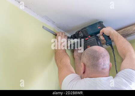 Fixation au guide mural pour un plafond extensible. Les réparateurs font l'installation d'un plafond extensible Banque D'Images