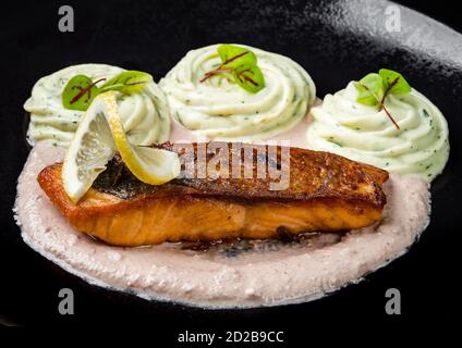 Saumon frit, poisson rouge, sauce géorgienne. Isolé sur fond noir. Banque D'Images