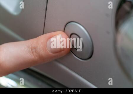 le doigt de la femme appuie sur le bouton pour activer le lavage gros plan de la machine Banque D'Images