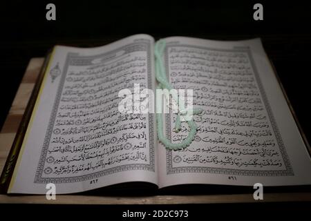 al-Coran est un livre Saint de l'orientation islamique isolé. Concept de religion. Une page ouverte de Coran sur un stand en bois au-dessus du tapis de prière page ouverte de Coran Banque D'Images