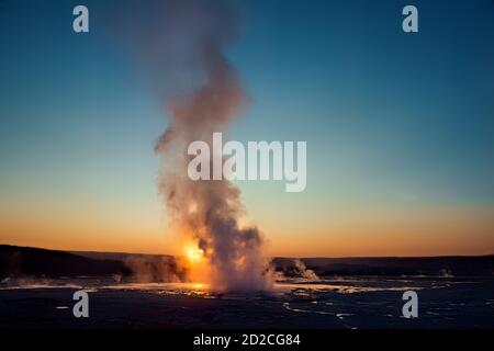 Le geyser de clopsydra éclate au coucher du soleil, bassin inférieur du Geyser, parc national de Yellowstone, Wyoming, États-Unis Banque D'Images