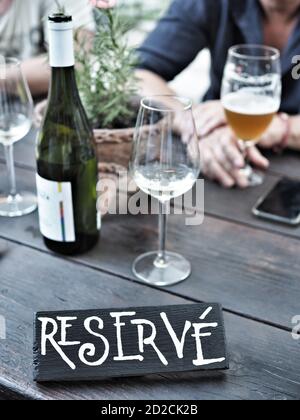 Panneau de table réservée au restaurant. Bouteille et verre de vin blanc, verre de bière sur table en bois. Banque D'Images