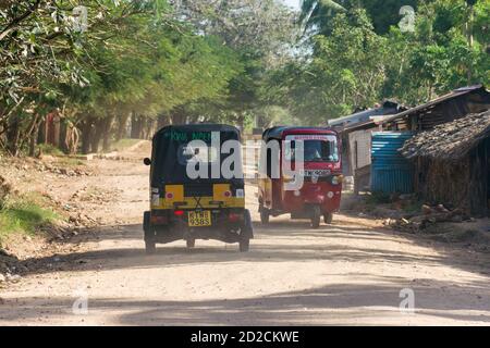 Tuk-tuks ou pousse-pousse auto le long d'une route de plage poussiéreuse, Diani, Kenya Banque D'Images