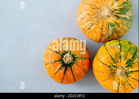 Vue de dessus de trois citrouilles mûres à motif varié sur une surface grise. Banque D'Images