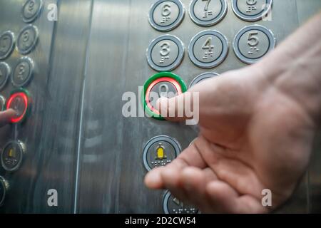 Le pouce appuie sur le bouton dans le plan rapproché du plancher zéro de l'élévateur. Les boutons de l'ascenseur sont signés en braille. Le concept d'inclusion. Banque D'Images