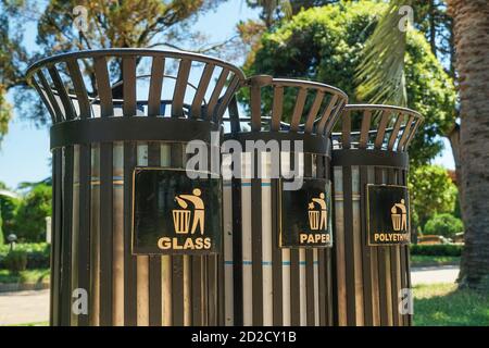 Conteneurs modernes en métal pour la collecte séparée des déchets dans le parc lors d'une journée ensoleillée en gros plan. Traduction : 'plastique, verre, papier.' Banque D'Images