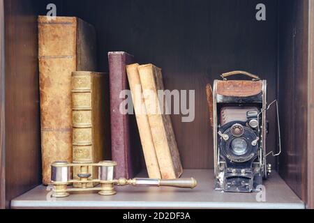 Vieux livres et un appareil photo sur une étagère vintage dans le placard, gros plan Banque D'Images