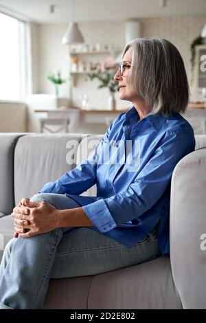 Chic décontracté mature femme âgée se reposant sur un canapé à la maison. Banque D'Images