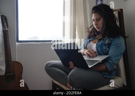 Fille travaillant dans un ordinateur avec une guitare Banque D'Images