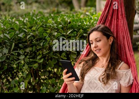 Femme lisant un livre électronique sur un Hammock Banque D'Images