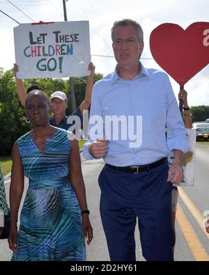 HOMESTEAD, FLORIDE - JUIN 27 : Bill de Blasio, maire de New York, un espoir présidentiel démocratique, Chirlane McCray se tient sur une échelle en regardant dans l'établissement qui tient des enfants migrants devant un centre de détention. Le centre de détention controversé à but lucratif accueille environ 2,300 enfants âgés de 13 à 17 ans, qui ont été placés sous la garde du ministère de la Santé et des Services sociaux après avoir été détenus à la frontière le 27 juin 2019.le 26 juin 2019 à Homestead Florida personnes : Bill de Blasio, maire de NY, Chirlane McRay crédit: Hoo-me / MediaPunch Banque D'Images