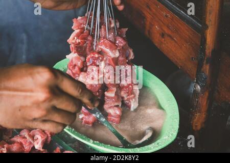 Donner du curry pour faire du satay de chèvre, du satay d'agneau, de l'agneau ou de la viande satay de chèvre avec de la viande crue. Satay traditionnel Klatak de Yogyakarta, Indonésie. Banque D'Images