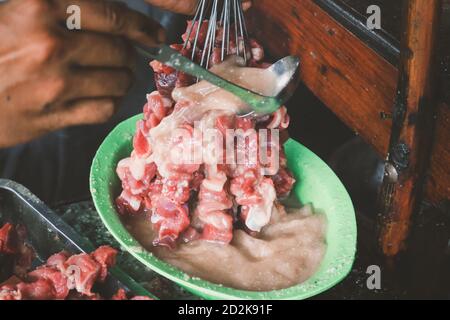 Donner du curry pour faire du satay de chèvre, du satay d'agneau, de l'agneau ou de la viande satay de chèvre avec de la viande crue. Satay traditionnel Klatak de Yogyakarta, Indonésie. Banque D'Images