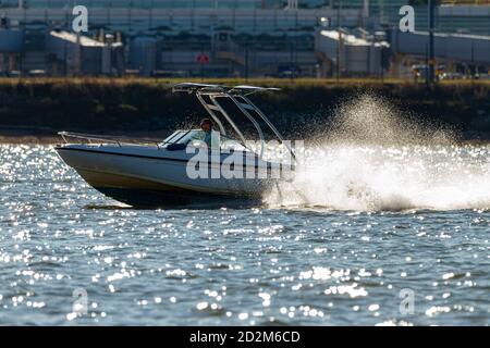 Washington DC, Etats-Unis 10/03/2020: Un bateau à moteur de style croiseur de cabine (Dauntless 20) navigue à grande vitesse sur le fleuve Potomac avec beaucoup de splash à venir b Banque D'Images