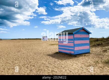 Cabines de plage Great Yarmouth en été, cabine britannique traditionnelle sur une côte est anglaise, bandes horizontales bleues et roses, ciel avec nuages Banque D'Images