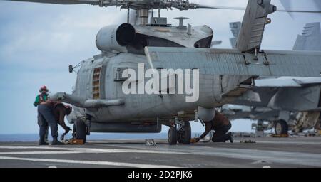 Des marins affectés à l’escadron de frappe maritime des Saberhawks de l’hélicoptère (UGH) 77 calent et enchaînent un Haucon MH-60R sur le pont de vol du seul USS Ronald Reagan déployé par l’avant de la Marine (CVN 76). Ronald Reagan, le navire amiral du Carrier Strike Group 5, fournit une force prête au combat qui protège et défend les États-Unis, ainsi que les intérêts maritimes collectifs de ses alliés et partenaires dans la région Indo-Pacifique. (É.-U. Photo marine par Jason Tarleton, spécialiste des communications de masse, 3e classe) Banque D'Images