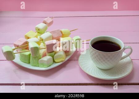 Tasse de café aromatique americano et assiette avec guimauves sur table en bois rose. Petit déjeuner confortable dans un style romantique. Banque D'Images