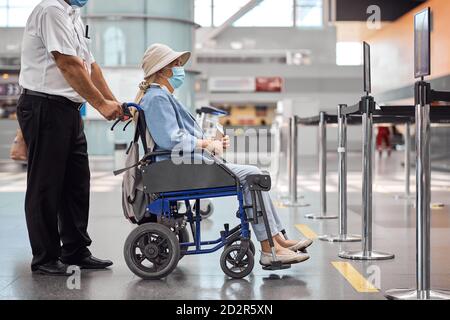 Employé d'aéroport roulant avec une femme âgée Banque D'Images